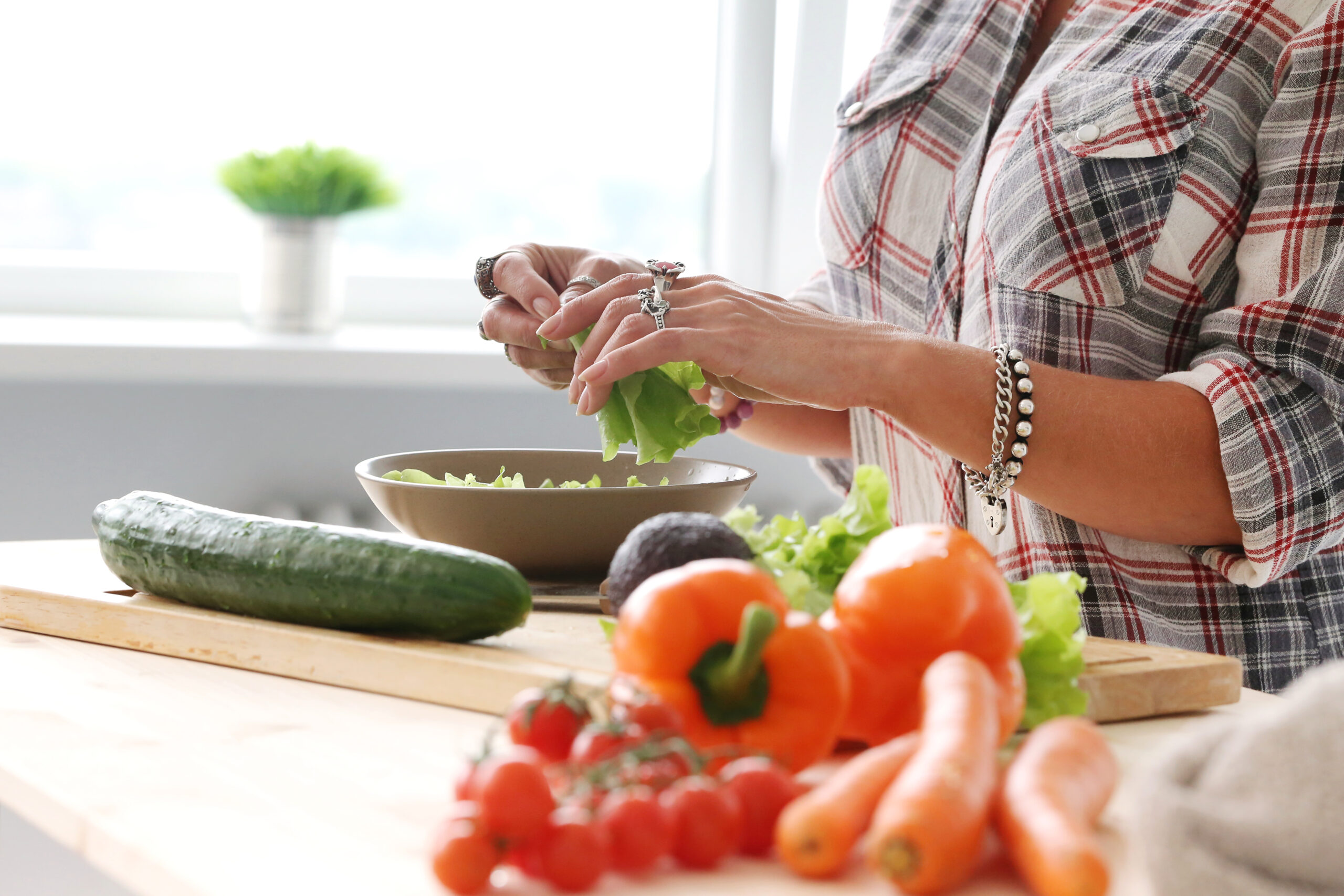 cancer prevention habits — woman preparing fresh vegetables in kitchen