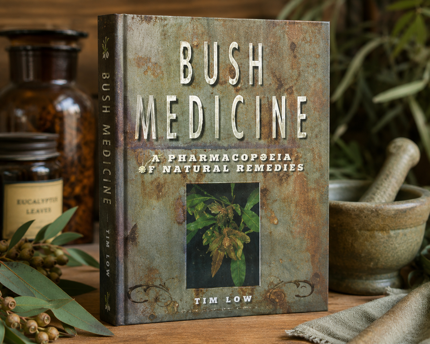 Tim Low's Bush Medicine: A Pharmacopoeia of Natural Remedies, displayed on a wooden surface surrounded by apothecary-style glass jars, dried herbs, a stone mortar and pestle, and neutral linen cloth
